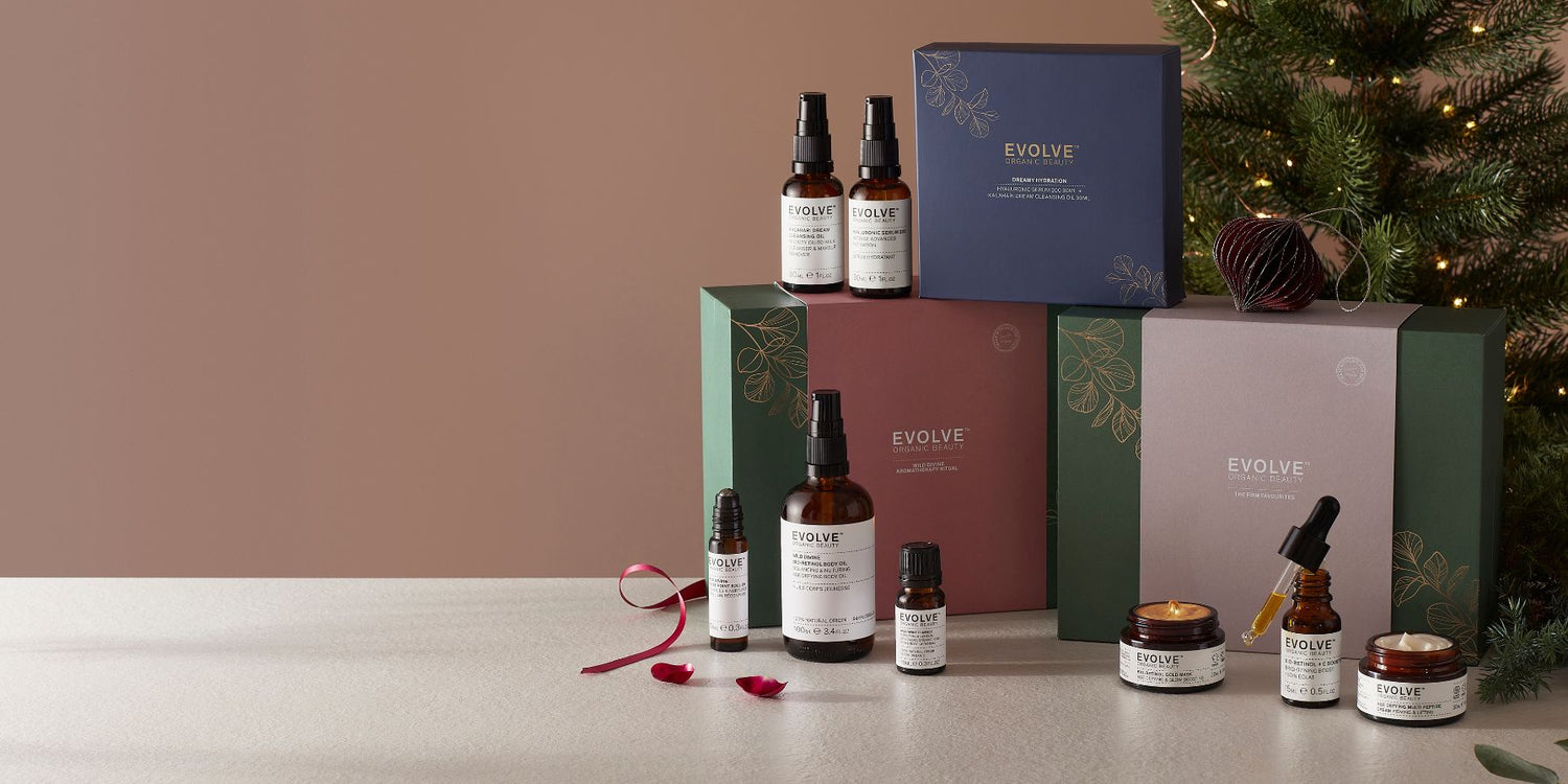 image of evolve beauty christmas sets infront of christmas tree with ribbon and products surrounding them