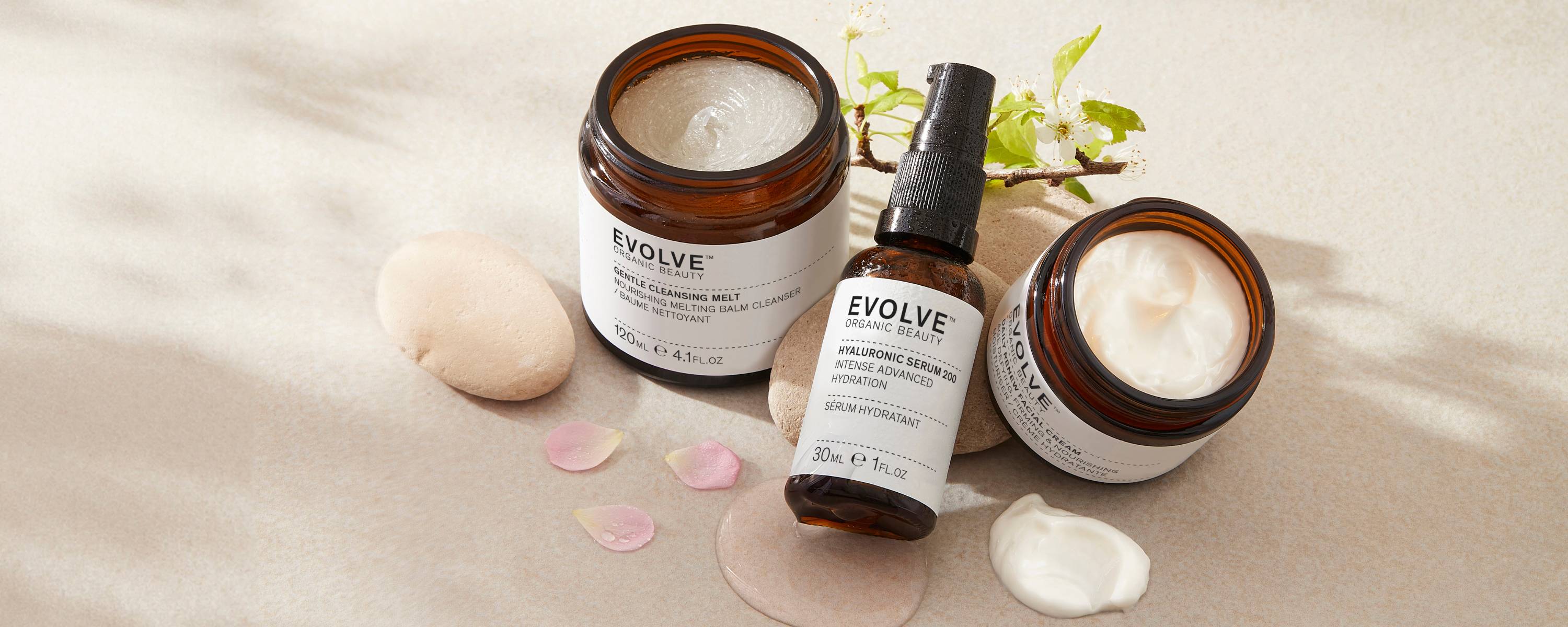 evolve organic beauty group shot of products on pebbles with flower petals