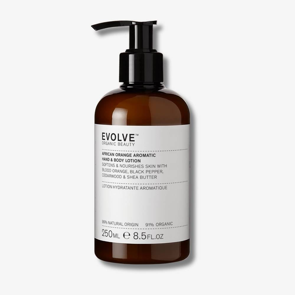 Evolve Organic Beauty African Orange Aromatic Hand & Body Loton in brown bottle with black pump lid on with an off white background with shadow behind