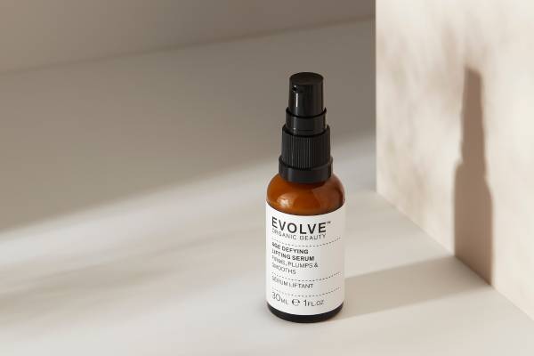 evolve organic beauty age defying lifting serum on concrete shelf in front of wall with shadow