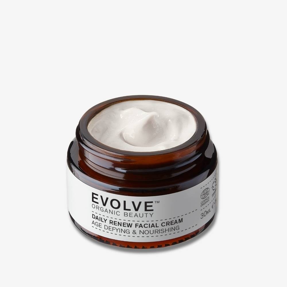 Open amber jar showing the texture of Evolve Organic Beauty Daily Renew Facial Cream travel size on an off white background with shadow behind