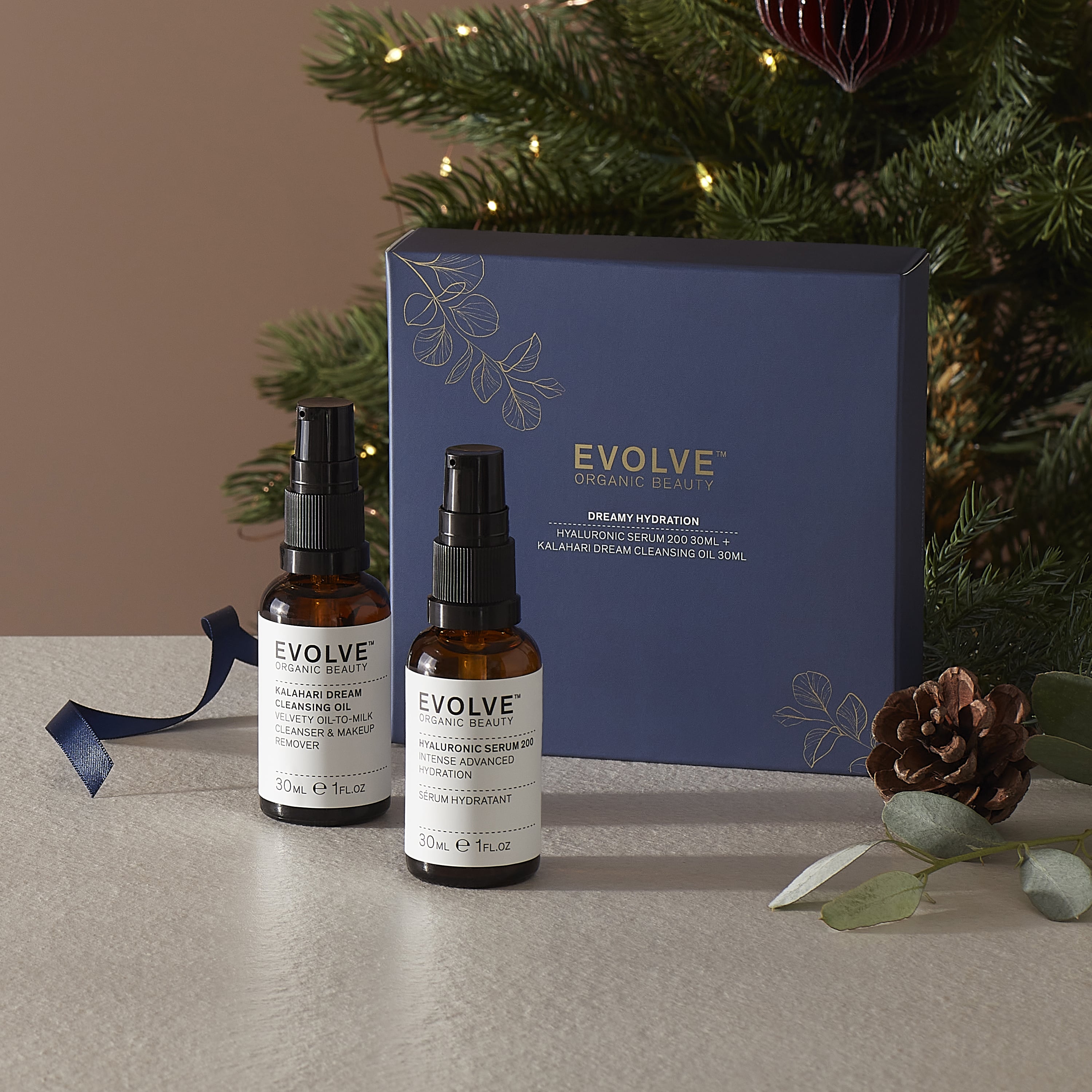 Dreamy hydration duo with Hyaluronic Serum 200 and Kalahari Dream Cleansing oil on a table with a decorative box and Christmas tree in the background.