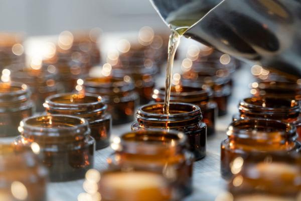 pouring artisinally made skincare into amber glass jars