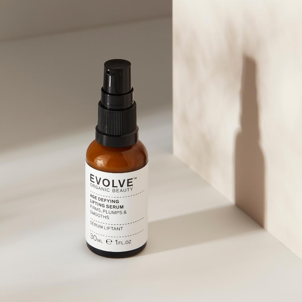 age defying liftin serum bottle with black pump on a beige background with shadows
