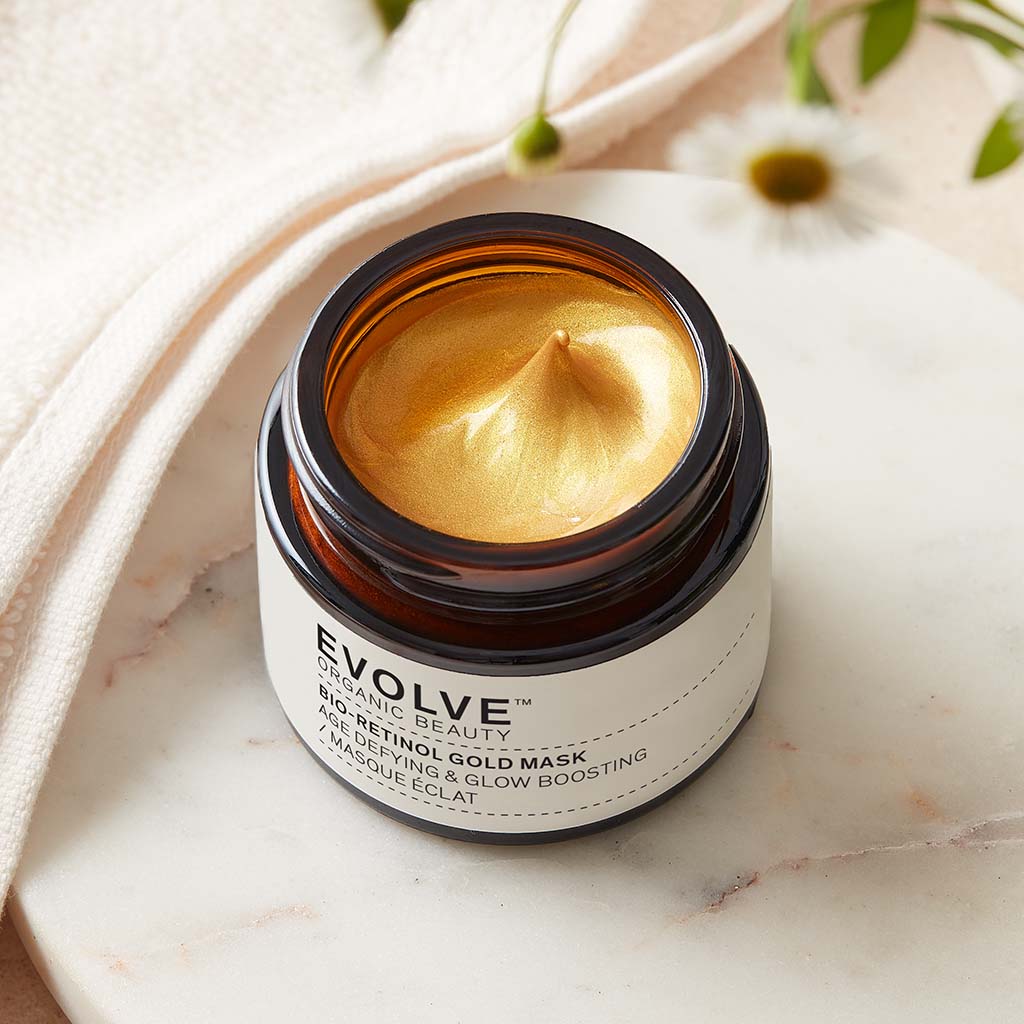 bio-retinol gold mask image showing bright gold rexture on marble coaster with bidens pilosa flower in the foreground and on marble coaster with towel