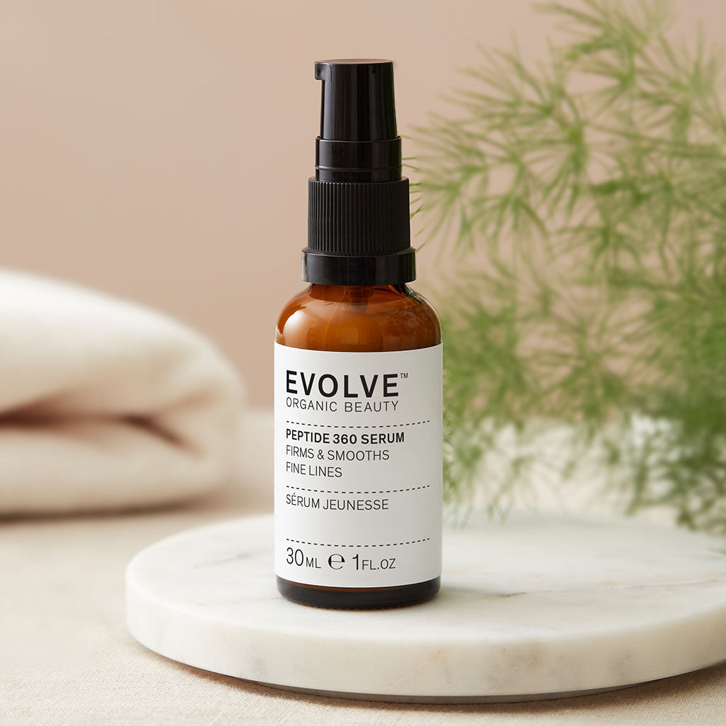 bottle of peptide 360 serum on top of marble like coaster with a green plant in a soft focus in the background