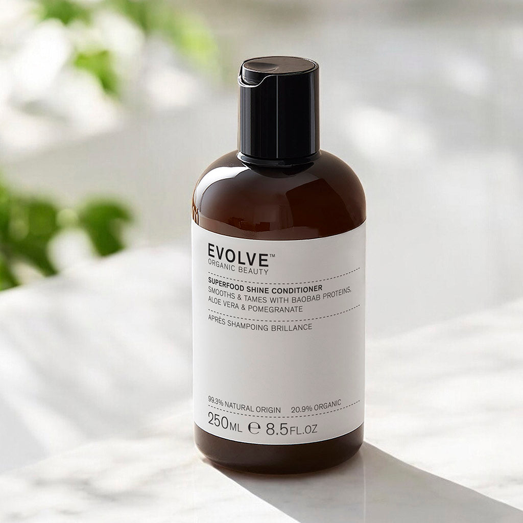 Bottle of Superfood Shine Conditioner 250ml on a marble surface in dappled sunlight with a soft-focus green plant in the background