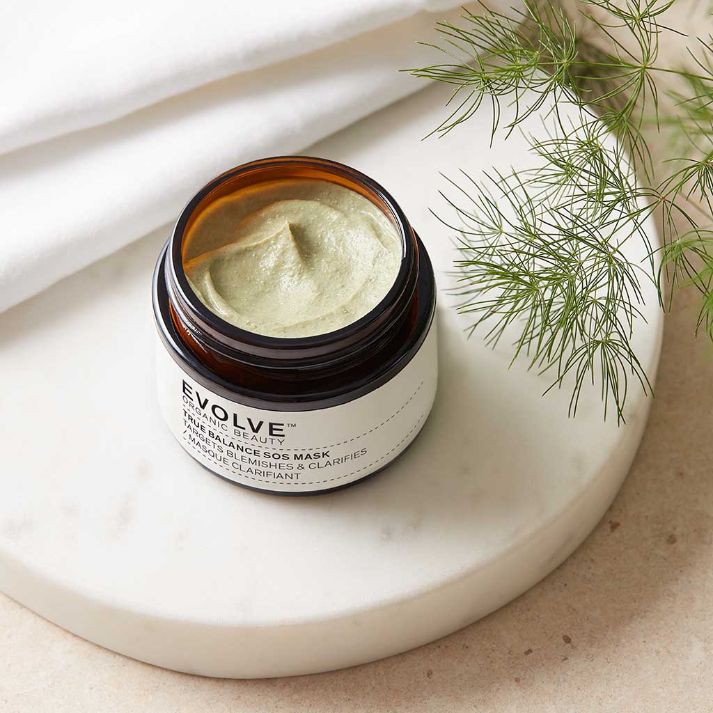 open jar of true balance sos mask showing soft green texture on marble coaster with greenery to right hand side
