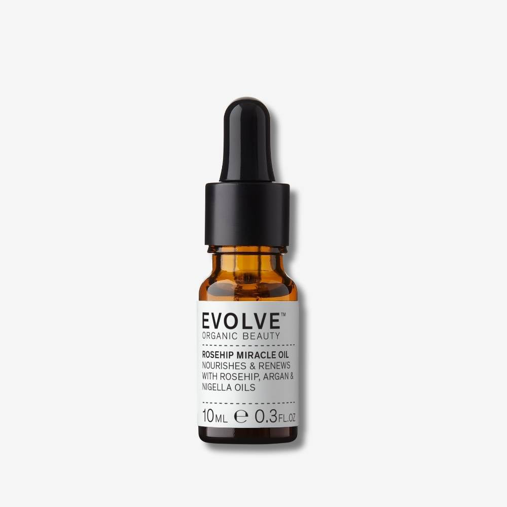 Evolve Organic Beauty Rosehip Miracle Oil in brown glass bottle with black pump lid on off white background with shadow behind