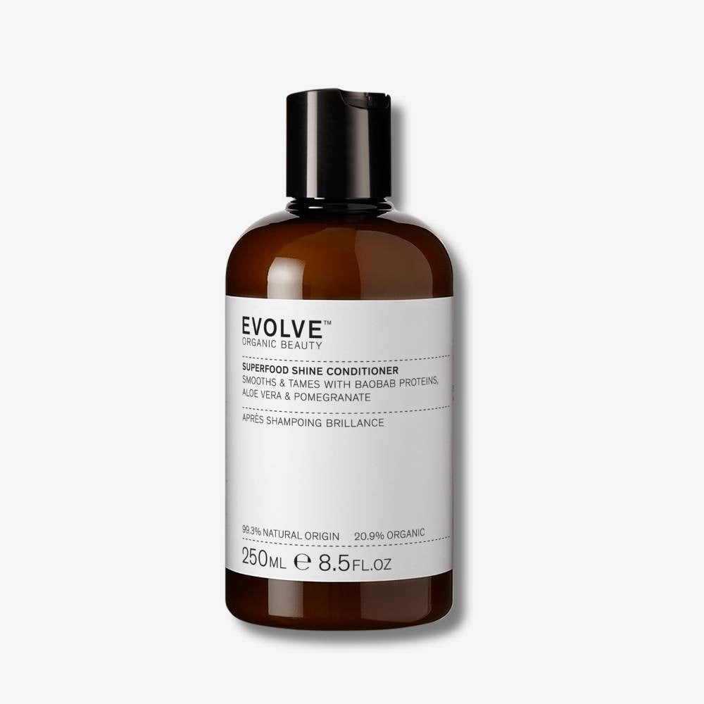 Evolve Organic Beauty Superfood Shine Conditioner in brown bottle with black disc cap lid on off-white background with shadow behind