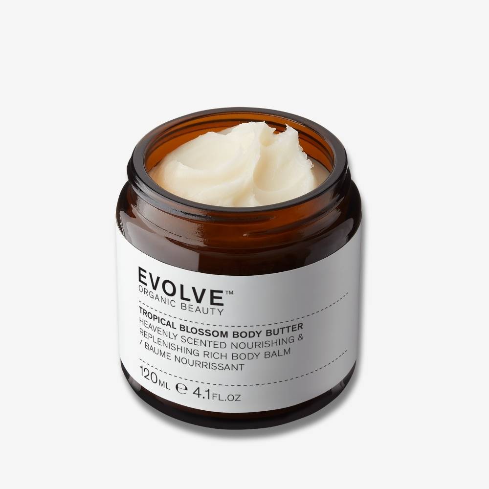 Evolve Organic Beauty Tropical Blossom Body Polis in brown glass jar with buttery texture on off white background with shadow behind