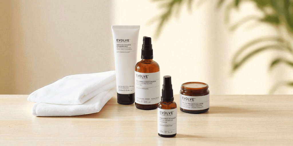image showing four skincare products on wooden table with plant in background