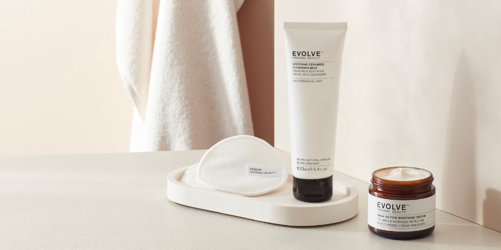 cleansing milk and sensitive face cream on modern stone table with bamboo face pads