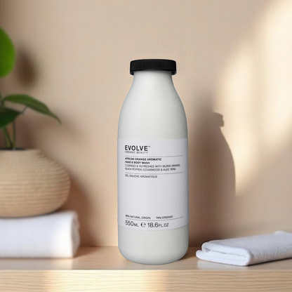 african orange aromatic hand and body wash in fiber based recyclable bottle on wooden table with white towels and plant