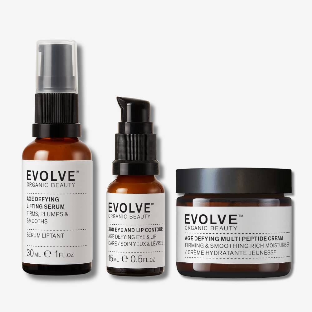 Evolve Organic Beauty age defying lifting serum in brown glass bottle with black pump lid, 360 eye and lip contour n brown glass bottle with black pump lid and age defying multi peptide cream in brown glass jar on off white background with shadow behind