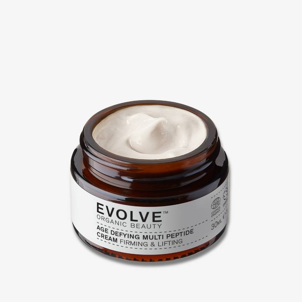 Evolve Organic Beauty Age defying multi peptide cream in brown glass jar with white creamy texture on off white background with shadow behind