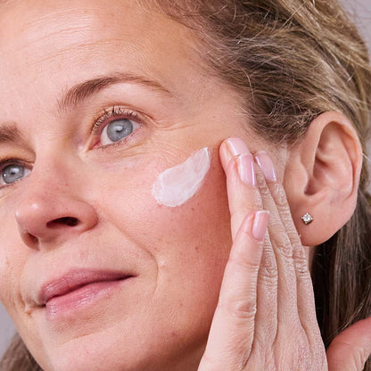 model applying age defying multi peptide cream on cheeck