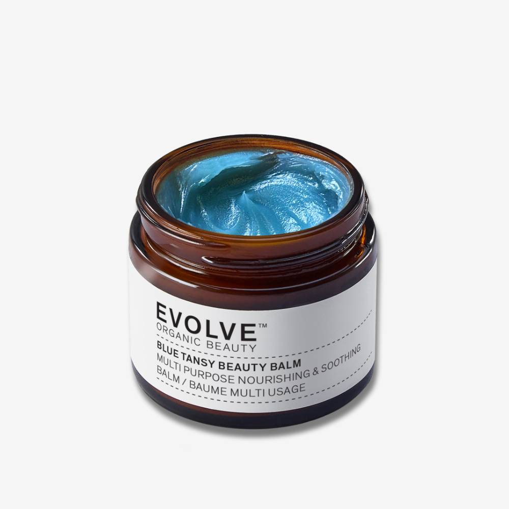 Evolve Organic Beauty Blue Tansy Beauty Balm in brown open jar with blue balm on off white background with shadow behind