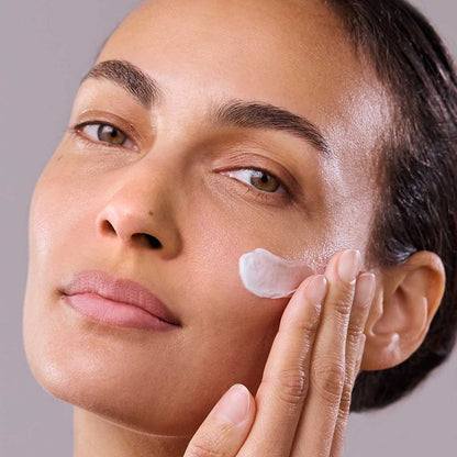 Close up of model applying Daily Renew Facial Cream to her cheek
