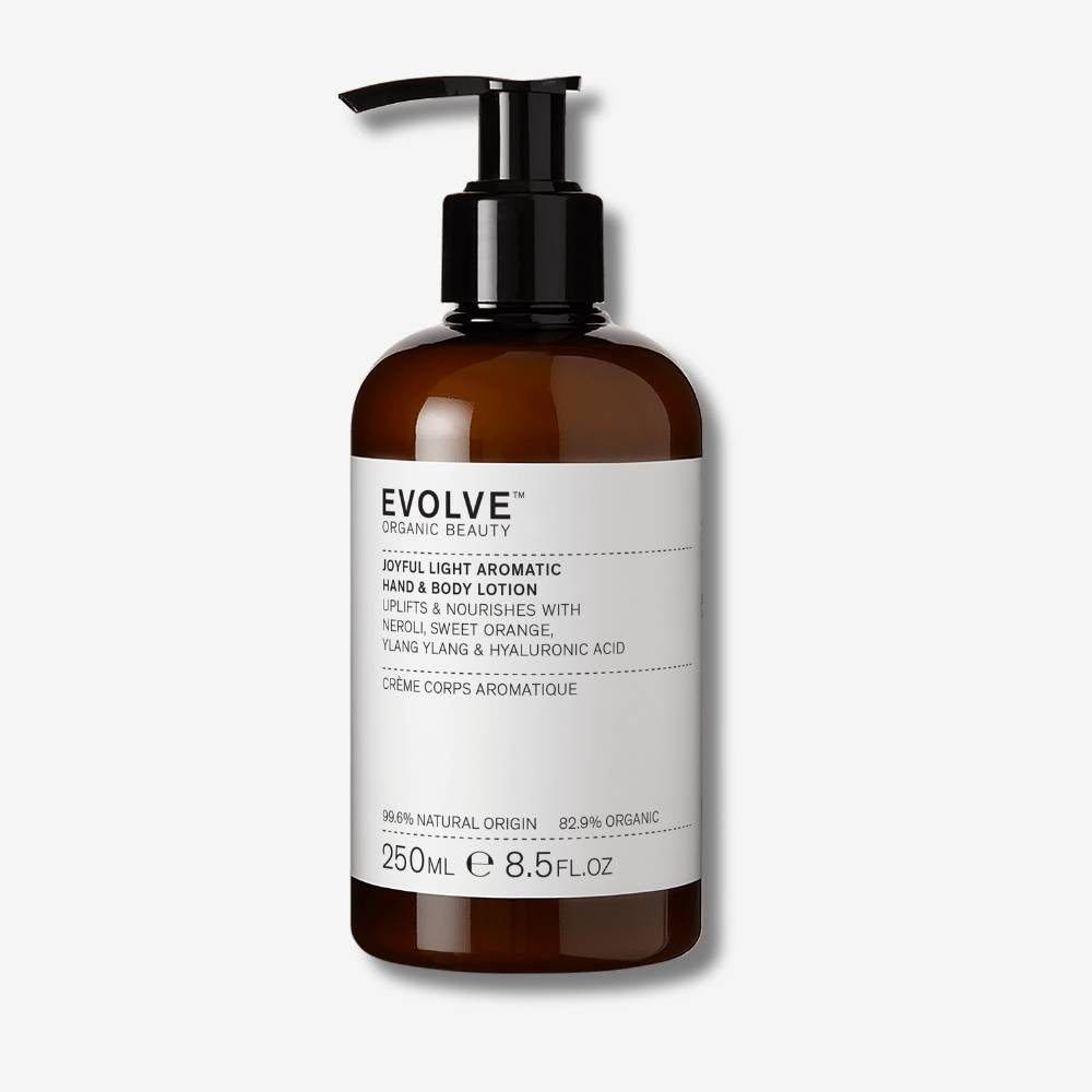 Evolve Organic Beauty Joyful Light Hand &amp; Body Lotion in brown prevented ocean plastic bottle with black pump on off white background with shadow behind