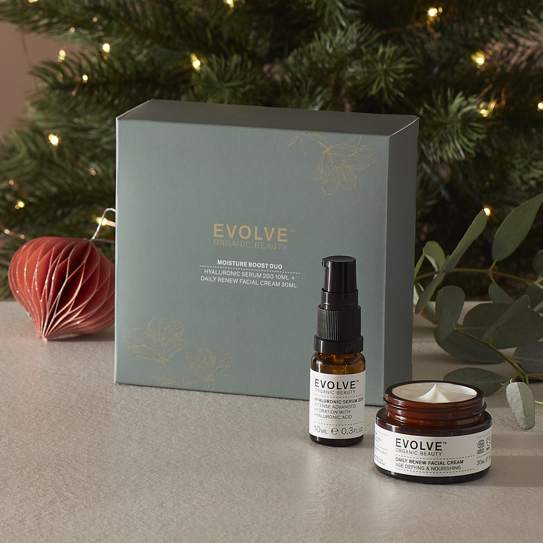 Evolve organic beauty moisture boost duo inlcuding hyaluronic serum 200 and daily renew facial cream with a decorative box against a festive background