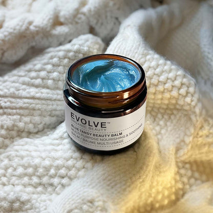open jar of Blue Tansy Beauty Balm on top of soft white knitted blanket 