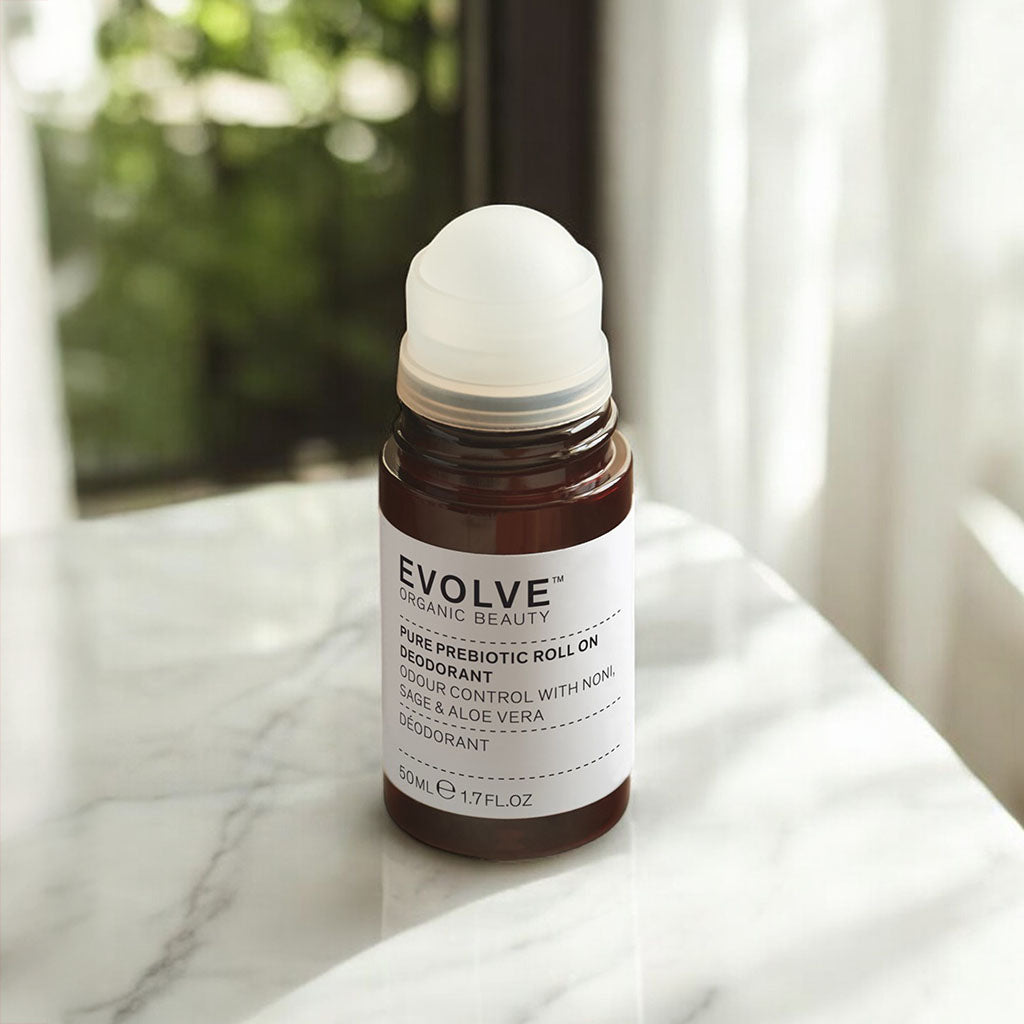 Open bottle of Pure Prebiotic Roll On Deodorant on a marble suface with a window behind with mottled greenery