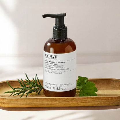 bottle of pure tranquility aromatic wash  on wooden tray with rosemary and geranium leaves on beige background