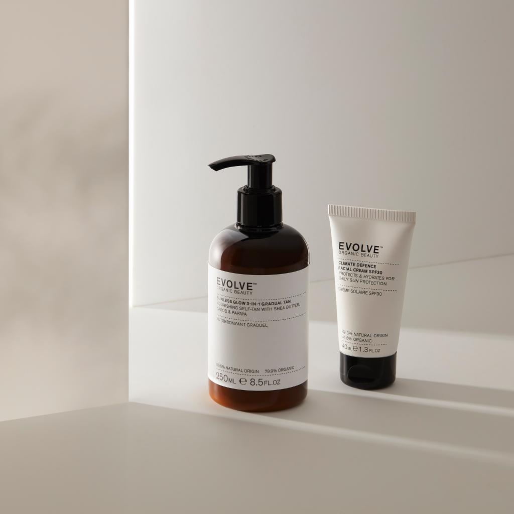evolve organic beauty climate defence facial cream SPF 30 next to sunless glow 3-in-1 gradual tan on beige countertop with shadows