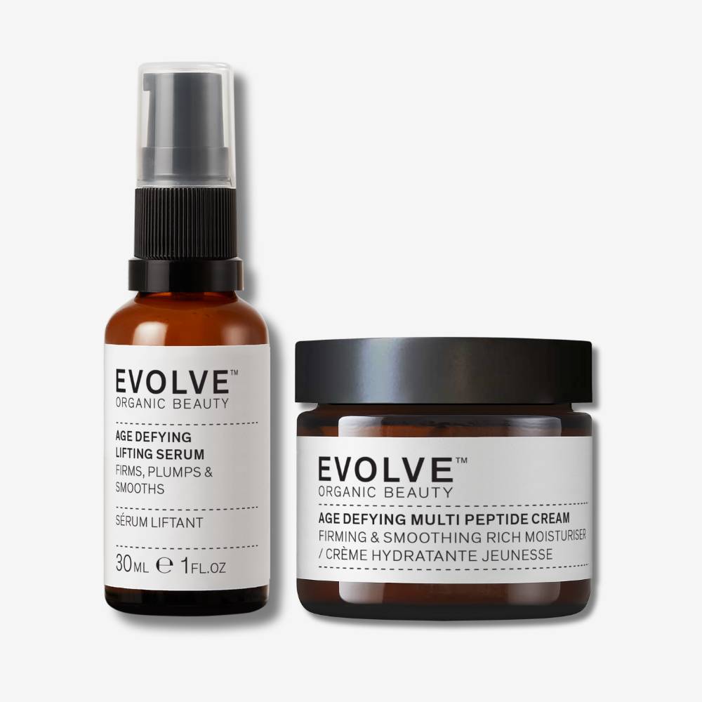 age defying lifting serum in brown glass bottle and age defying multi peptide cream in brown glass jar on off white background with shadow behind