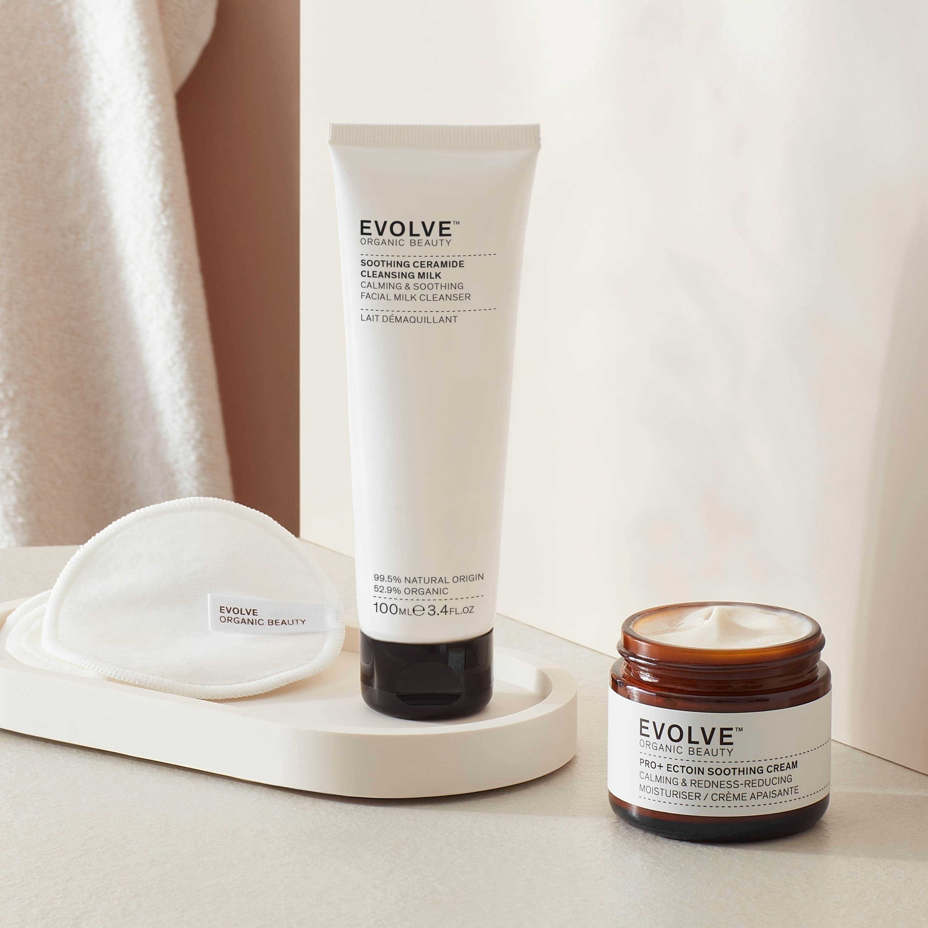 sensitive skin rescue duo bundle including soothing ceramide cleansing milk in sugarcane tube and pro+ ectoin soothing cream in brown glass jar with black lid in a bathroom setting with towel in the backgrounds products on a marble coaster and reusable bamboo pads