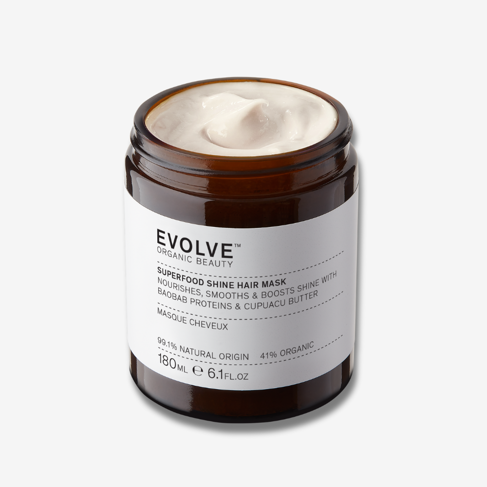 An open jar of Evolve Superfood Shine Hair Mask in a brown glass jar on an off-white background with a soft shadow behind