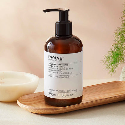 Evolve organic beauty Vital Clarity aromatic lotion in Brown bottle with cap on a wooden tray with green towel on a beige background
