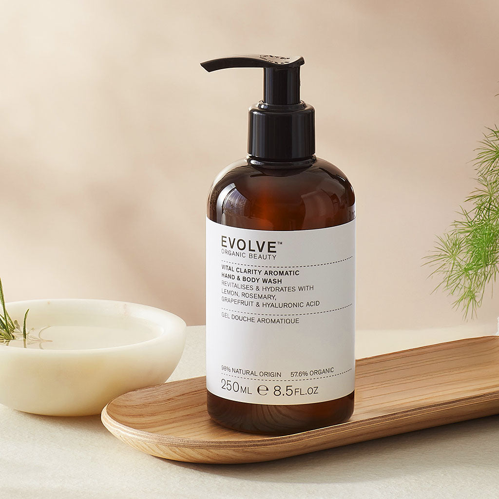 Evolve organic beauty Vital Clarity Aromatic Lotion in Brown bottle with pump on a wooden tray with green towel on a beige background
