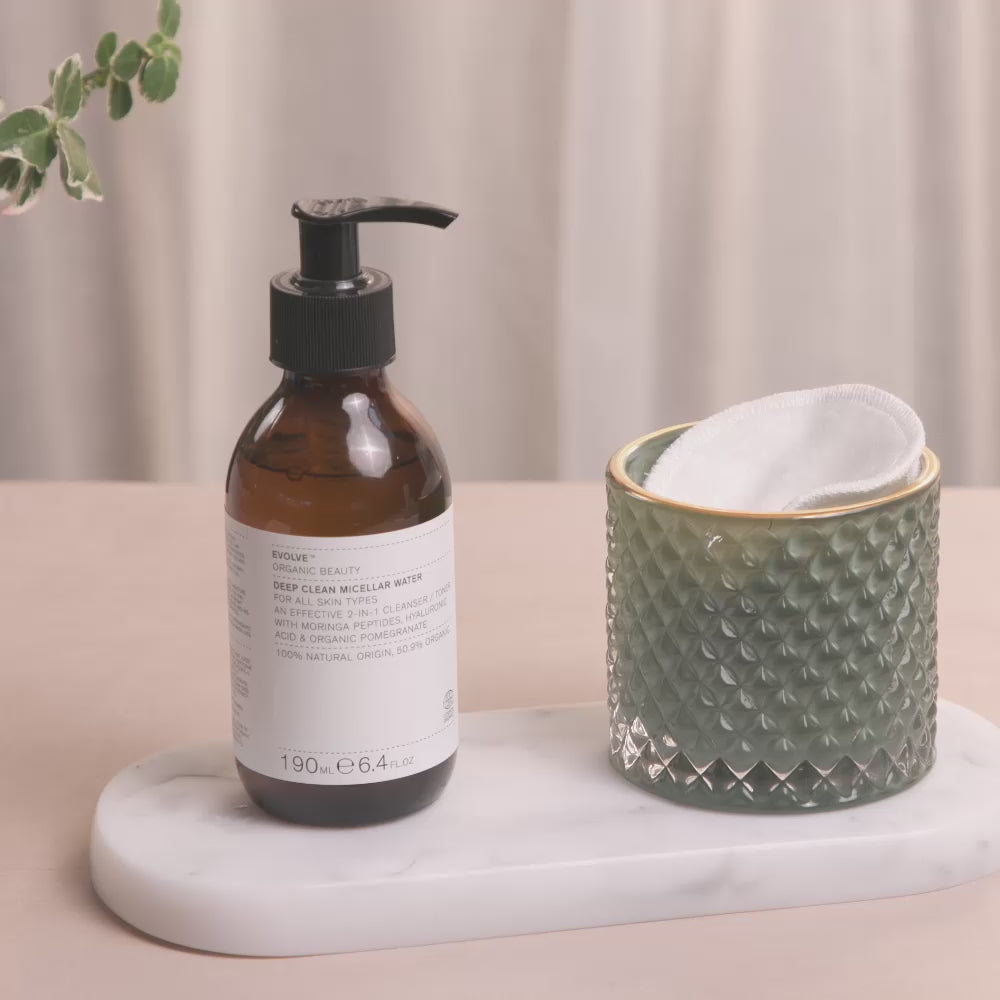 Video of a woman taking a Reusable Bamboo Makeup pad and dispensing some Deep Clean Micellar Water onto the pad before using the pad to cleanse her cheek and then smile at the end